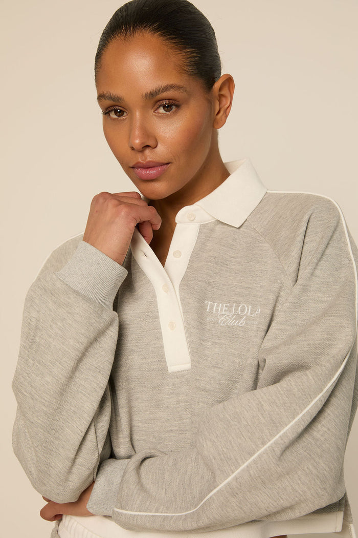 THE LOLA CLUB Grey melee · relaxed fit met polokraag en Lola Club logo. Zachte sweaterstof.